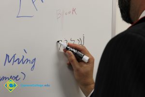 Someone writing on a whiteboard with black marker.