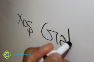 Someone writing on a whiteboard with black marker.