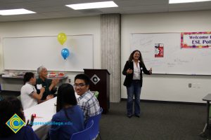 A woman is speaking to guests at the ESL potluck.