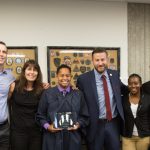 Various staff members with Rick Ram and a graduate holding an award.