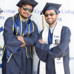 Two male graduates in graduation regalia.