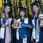 Three female graduates in cap and gowns and holding graduation stuffed animals with balloon and a CSU pennant.