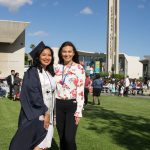 A female graduate in cap and gown standing with Kassandra Abreu.