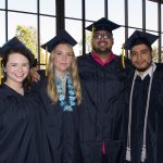 Students smiling in their graduation regalia.