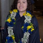 Young lady wearing graduation regalia and a floral money lei.