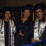 Three young ladies in their graduation regalia smiling.