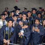 A group of graduating students in regalia smiling.