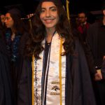 A smiling young lady in graduation regalia and a Student Athlete stole.