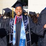 Graduate smiling with arms outstretched.