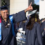 Graduate smiling and pointing up.