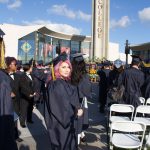 Graduate with purple hair looking back at camera.