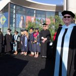 Dr. Cheryl Marshall in graduation regalia smiling with other graduates in the background.