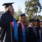 A group of graduates with one saluting during commencements.