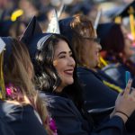 Smiling graduate seated among her fellow graduates.