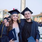 A smiling young man and a smiling young woman in graduation cap and gown.