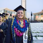 Smiling female graduate with several leis and an EOPS stole.