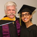 Professor Dave McCament and a woman with short hair and glasses wearing commencement regalia.