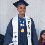 A smiling male graduate wearing an EOPS stole.