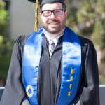 A male BSFS graduate with glasses in full regalia.