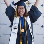 An EOPS graduate holding up her arms and smiling.