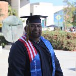 A male graduate in full regalia and a Veteran stole.