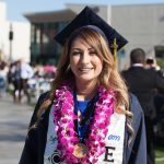 An EOPS graduate wearing a purple orchid lei.