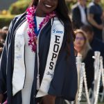 EOPS student wearing her graduation regalia, EOPS stole and purple orchid lei.