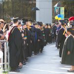 Staff and faculty standing along the aisle during commencement processional.