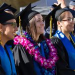 Students in their cap and gown smiling during commencement.