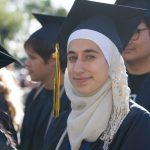 A young lady smiling in her cap and gown during commencement.