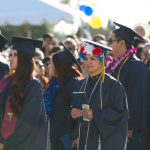 A group of students in their cap and gowns standing during commencement ceremony.