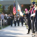 The Color Guard carrying flags walking in the commencement ceremony.