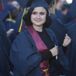 A smiling young lady wearing graduation regalia .