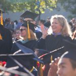 Kathleen Reiland standing among other faculty and staff in graduation regalia during commencement.