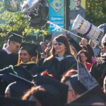 Faculty and staff in graduation regalia smiling during commencement.