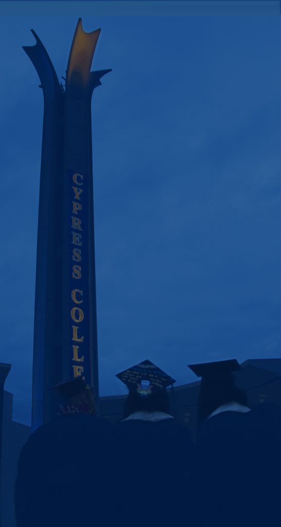 Graduating students stand facing the campanile at night