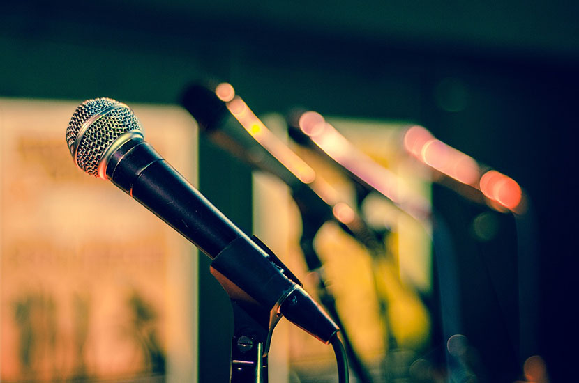 Microphones on stands lined up on stage