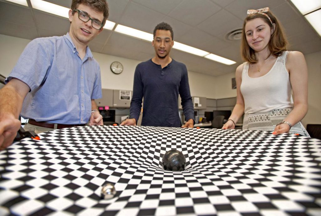 three people stand holding checkered cloth