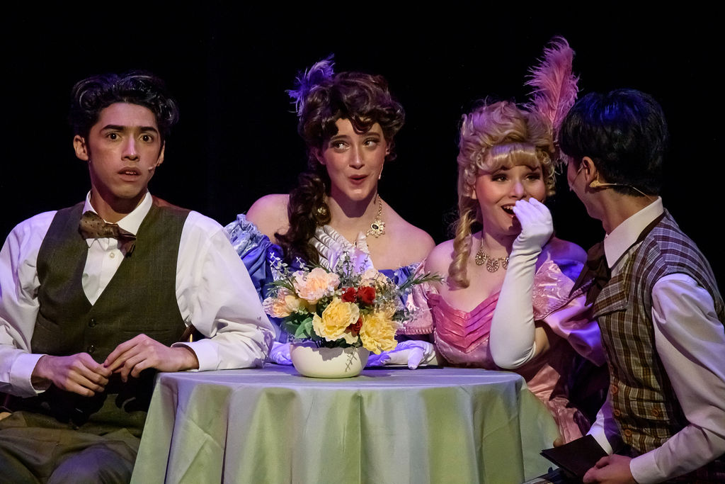 Two couples sit at a cafe table in the musical "Hello, Dolly!"