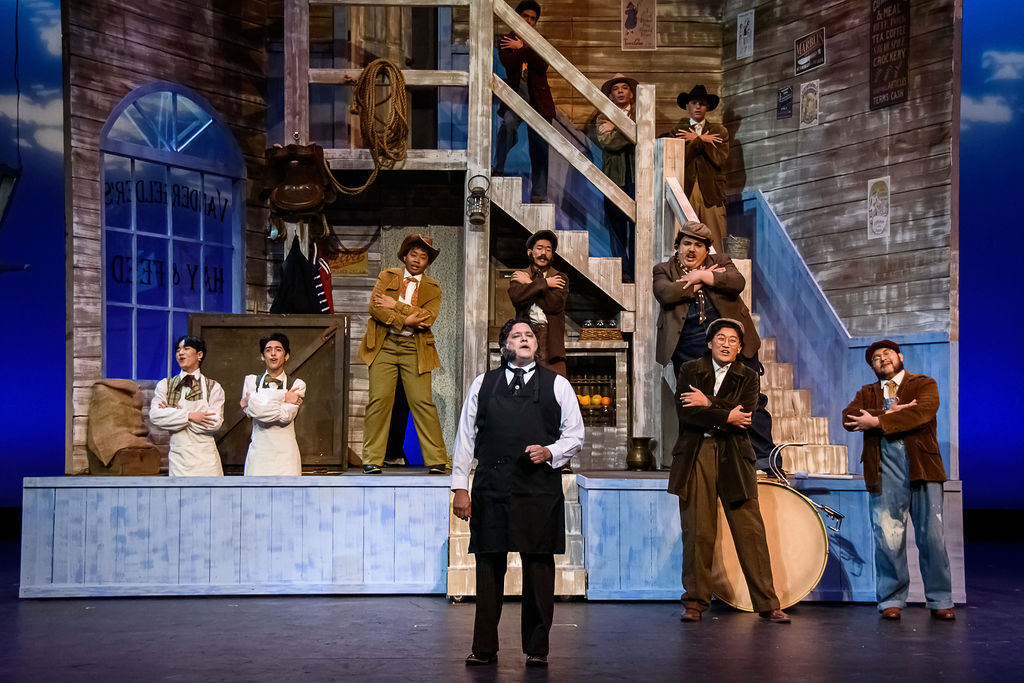 Actors perform as workers at a stage set of a turn-of-the-century general store in the musical "Hello, Dolly!"