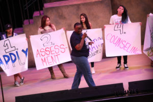Students on stage holding poster board signs