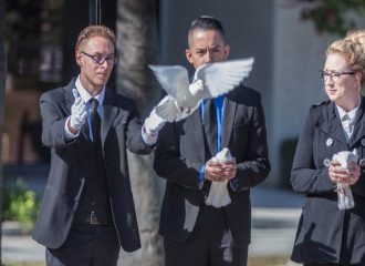 Three individuals holding and releasing doves