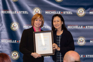 Dr. JoAnna Schilling with Congresswoman Michelle Steel. The two are holding an award which is being presented by Rep. Steel.