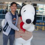 Smiling young man standing with Snoopy
