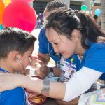 Nursing students listening to children's heart through stethoscope.