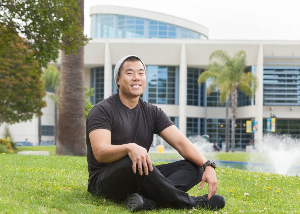 Student sitting on grass in front of library