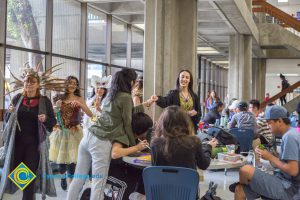 Group of students parading by students who are eating and studying.