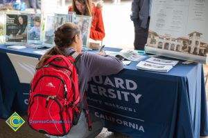 Student filling out paperwork at a Vanguard University table.