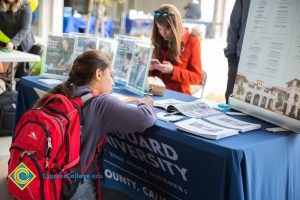 Student filling out paperwork at a Vanguard University table.