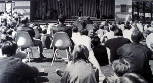 Students watching a performance on an outdoor stage
